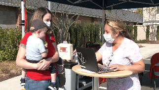 A mother discusses flu vaccination with a CHC healthcare provider at a drive-through clinic.