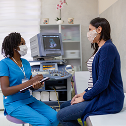 médica y mujer embarazada conversan sobre las vacunas contra la tosferina (Tdap), la influenza y el COVID-19