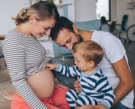father and mother hold young child touching pregnant belly for vaccine protection