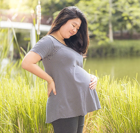 pregnant-woman-outside.jpg Pregnant woman standing outside holding her belly.