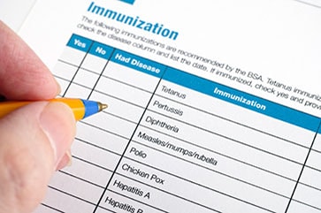 Vaccines by Disease putting pen to form for immunization records by disease