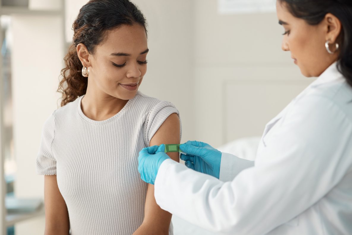 doctor putting a green band-aid on young lady