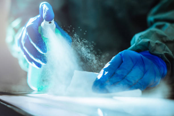 Person using spray bottle and gloves to clean and disinfect.