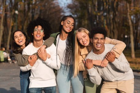 Positive group of young friends having fun at public park Image of two young women embracing