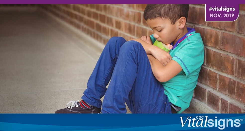 Adverse Childhood Experiences (ACEs) A child hugging a toy to his chest while sulking against a brick wall.