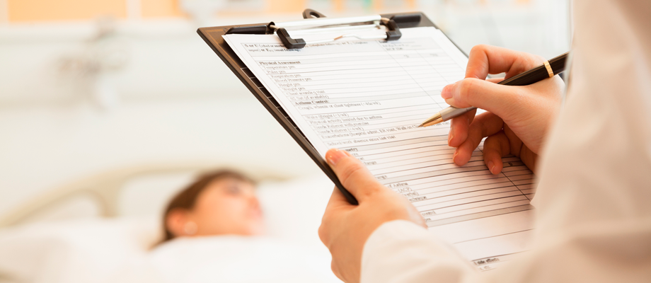 Health care professional writing on clip board and patient laying down on the background