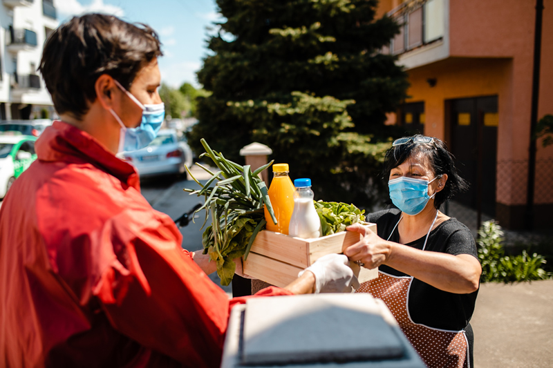 iStock-1222587457 (1) man wearing face covering making purchase from outdoor vendor, also wearing face covering