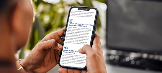 A person holding a mobile phone displaying the September 2023 Program Updates web page.