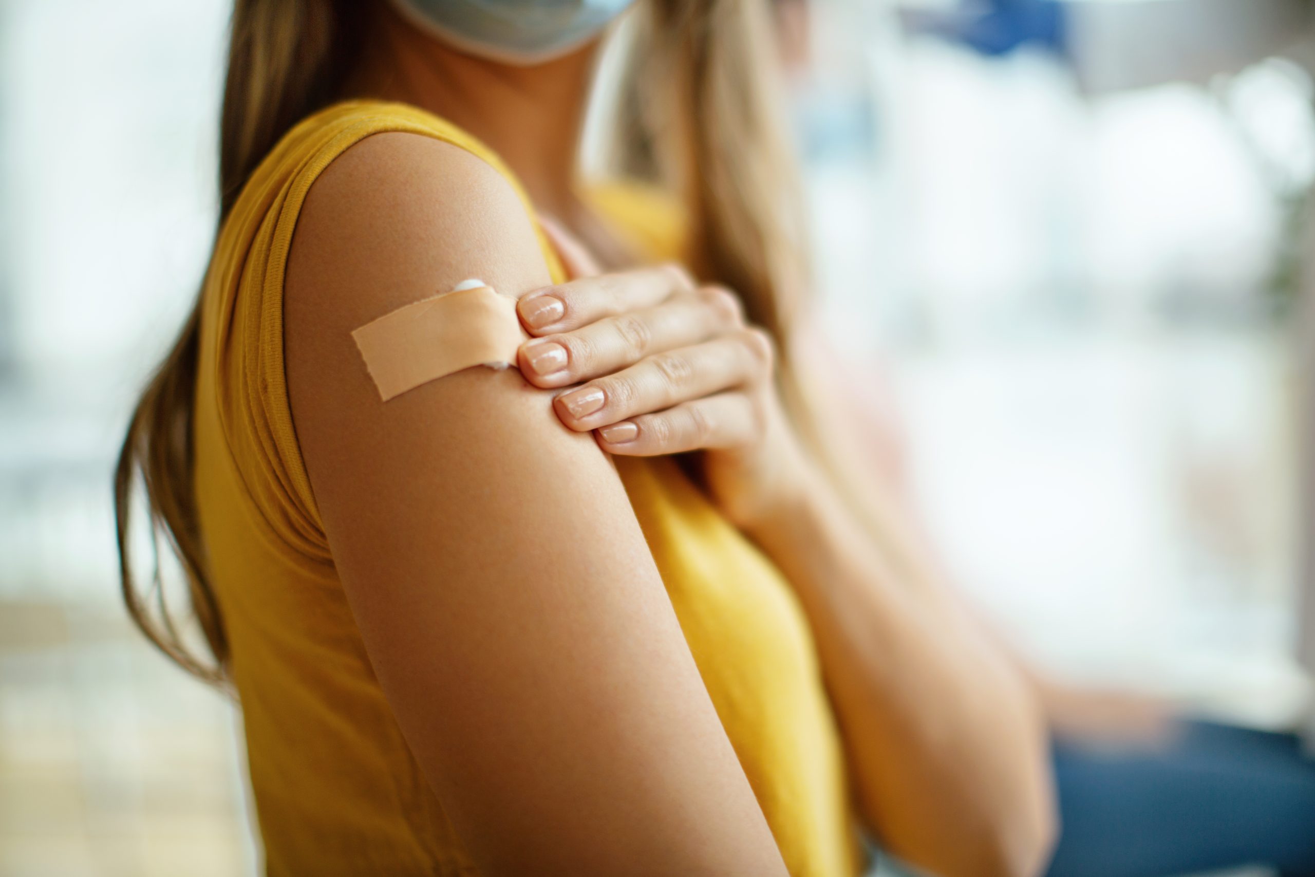Vaccinated traveler shows bandaid on arm.